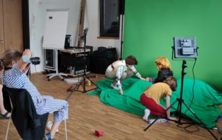 Kinder erstellen eine Szene vor einem Greenscreen und werden fotografiert