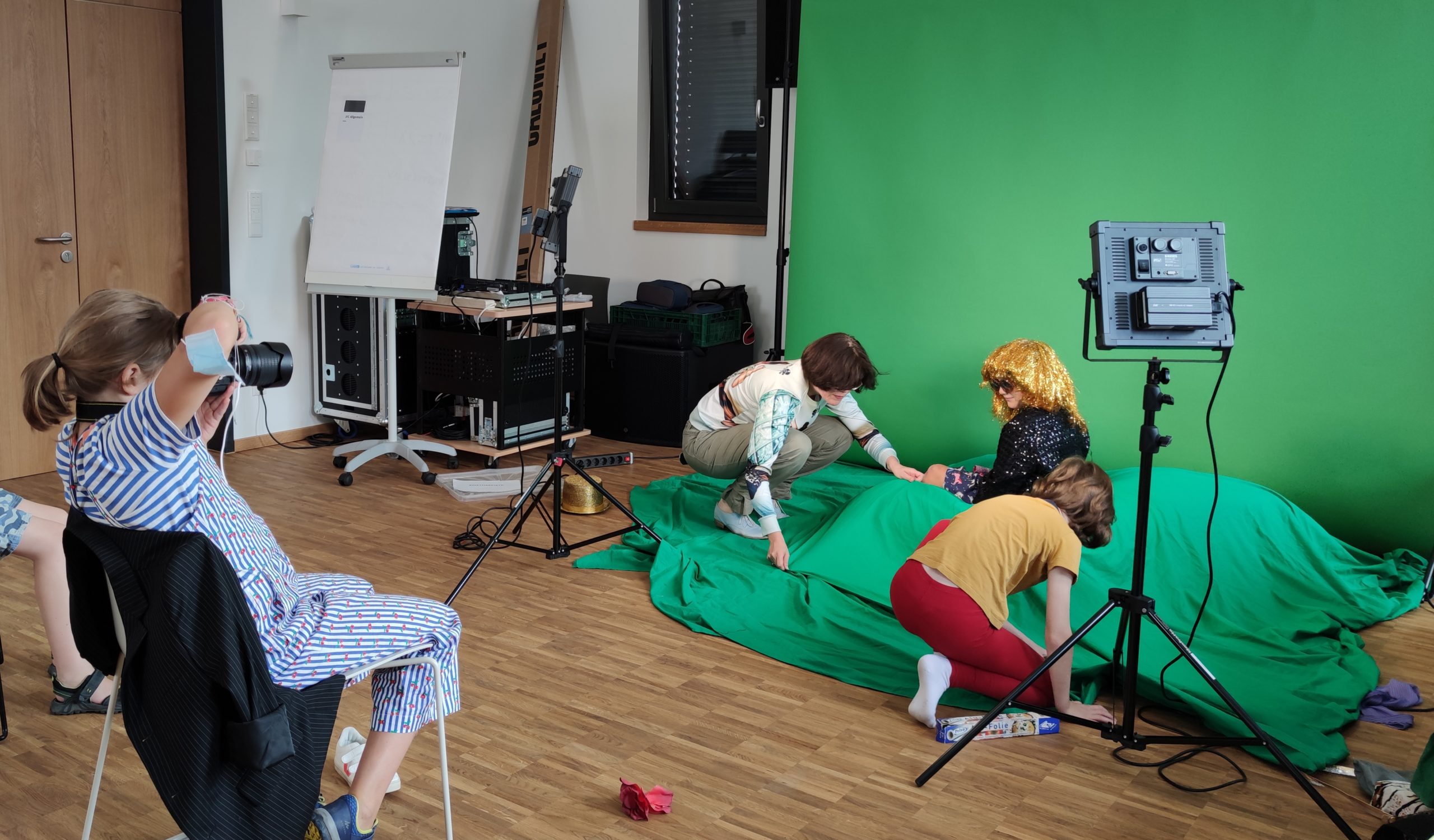 Kinder erstellen eine Szene vor einem Greenscreen und werden fotografiert